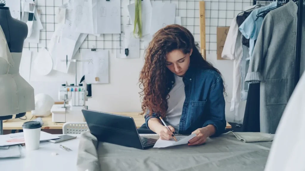 Person arbeitet am Laptop und plant Online Shop als Einstieg in E-Commerce Weiterbildung